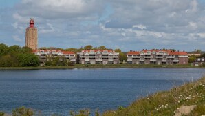 Ett hotell vid vattnet med flera byggnader, ett markant torn och en lugn sjö.