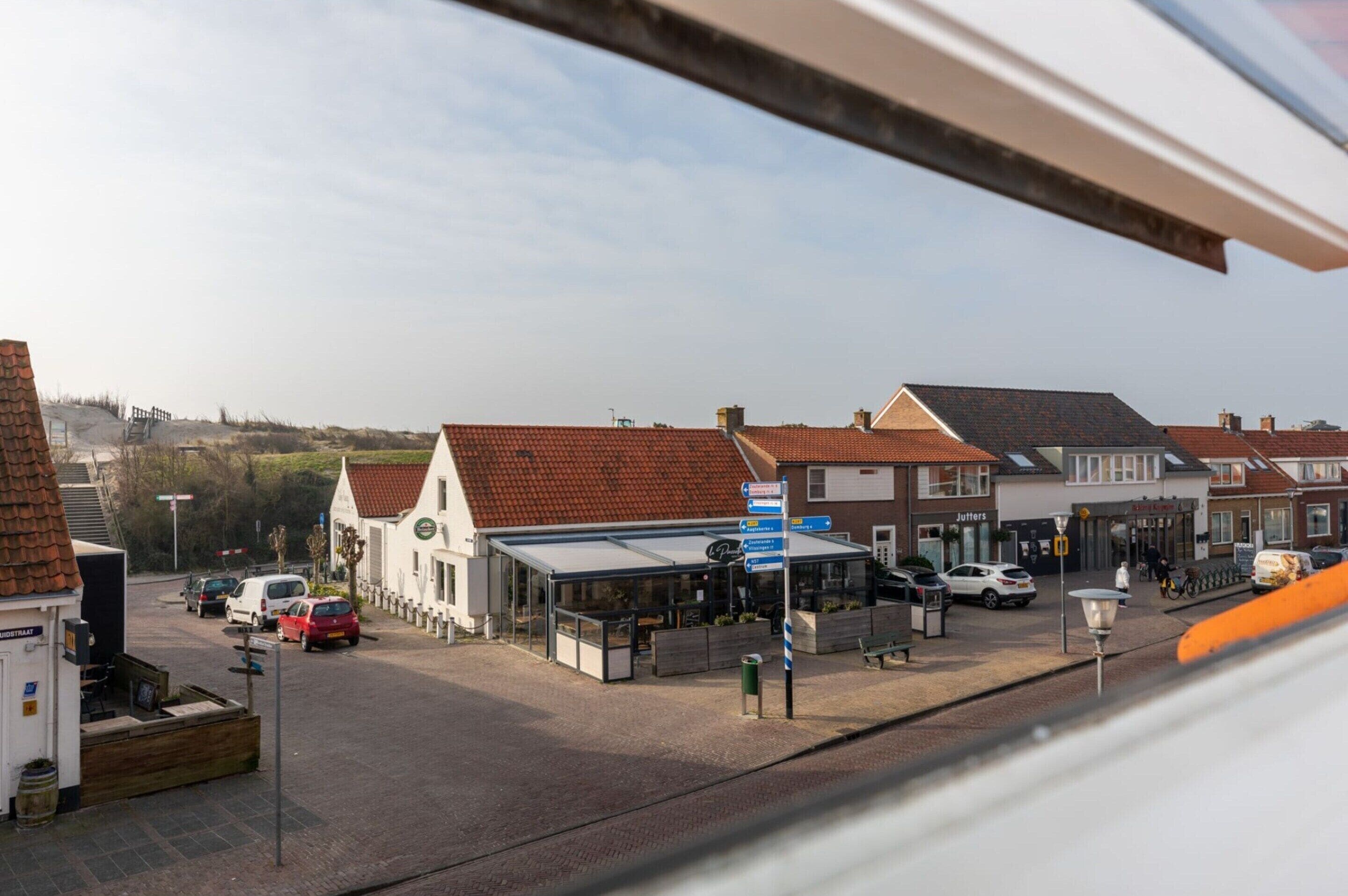 Ein Stadtplatz mit Bushaltestelle, Geschäften und einer Fußgängerüberweg.