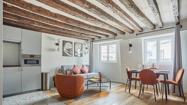 A modern kitchen with white cabinets, a built-in oven, and a stainless steel trash bin. - Charming Flat 1 Bedroom Le Marais Beaubourg (Paris)