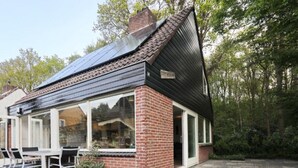 Una casa con fachada de ladrillo, ventanas amplias y techo de tejas.