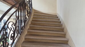 A concrete staircase with a black wrought iron railing, leading upwards.