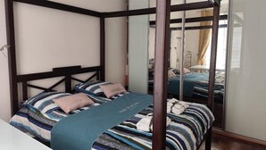 A four-poster bed with a striped bedspread and a blue throw blanket.