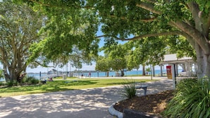 A park with a paved walkway, trees, and a view of the water. - Fairweather Dreaming on Welsby (BONGAREE)