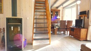 Ein Holzinnenraum mit Kamin, Treppe, Essbereich und Fernseher.