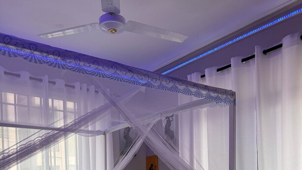 Un dormitorio con cama con dosel, ventilador de techo y mesita de noche.