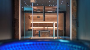 A modern interior with a glass partition, a central seating area, and a ceiling with recessed lighting. - Riserva Bianca Limone Hotel&SPA (Limone Piemonte)