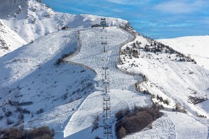 A snow-covered ski slope with a ski lift and a small cabin.