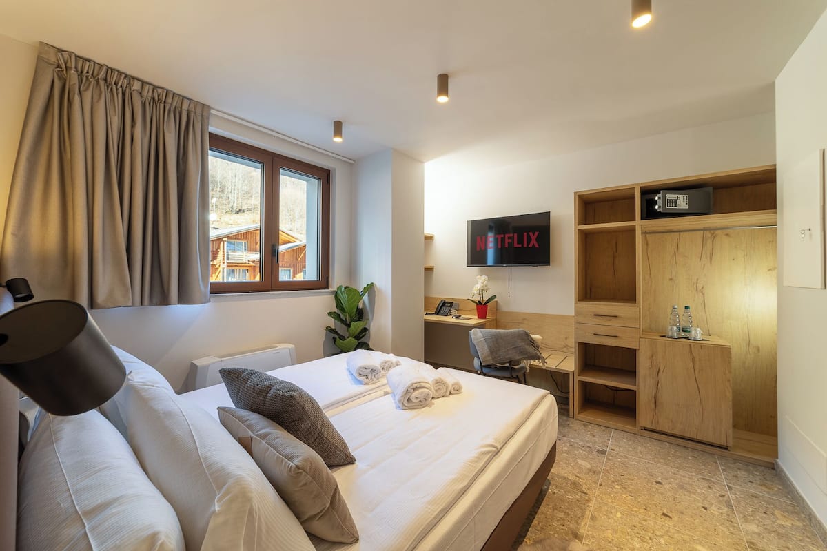 A hotel room with a bed, a desk, a TV, and a wardrobe.