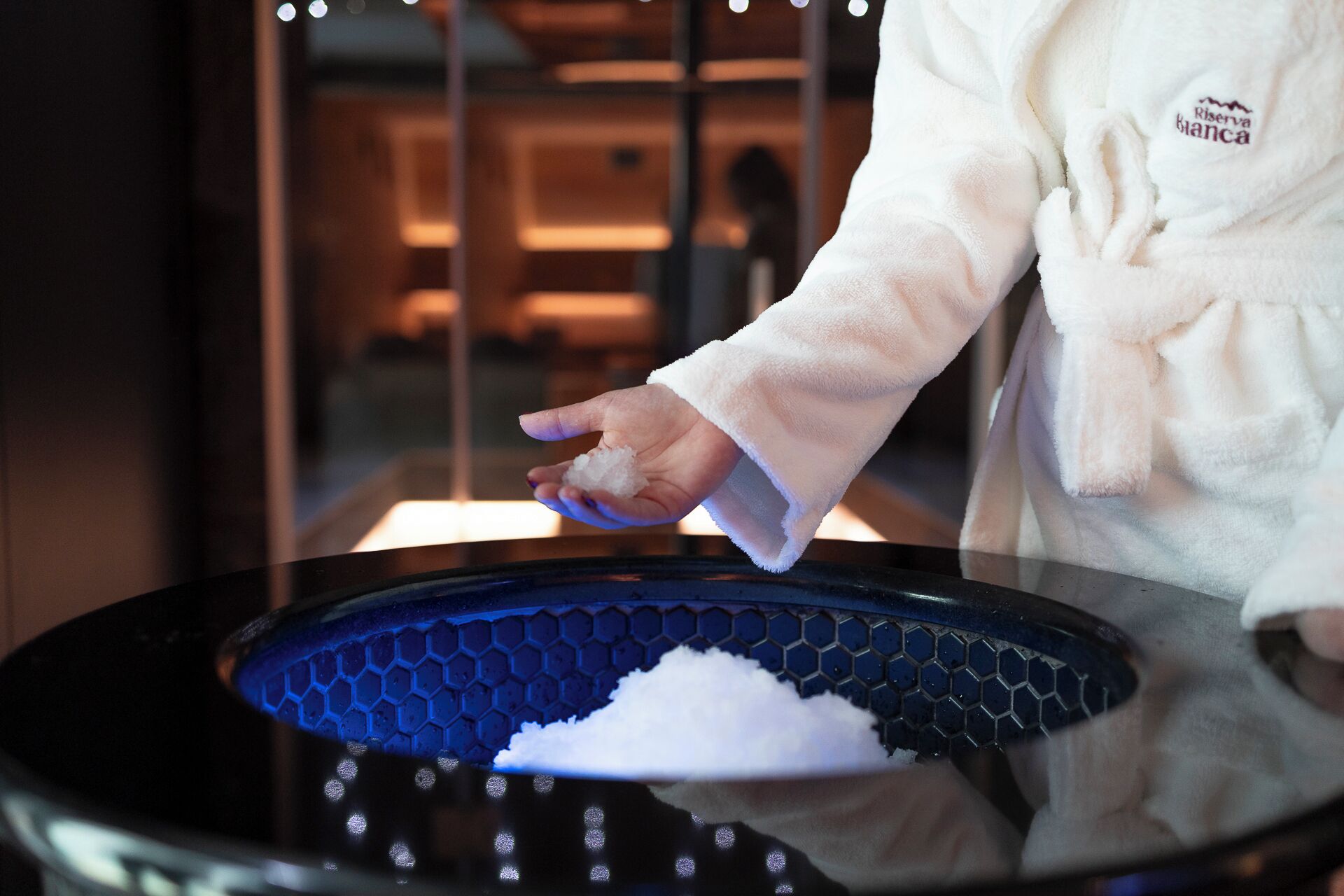 Une personne vêtue d’une robe blanche tenant un bol de sucre.