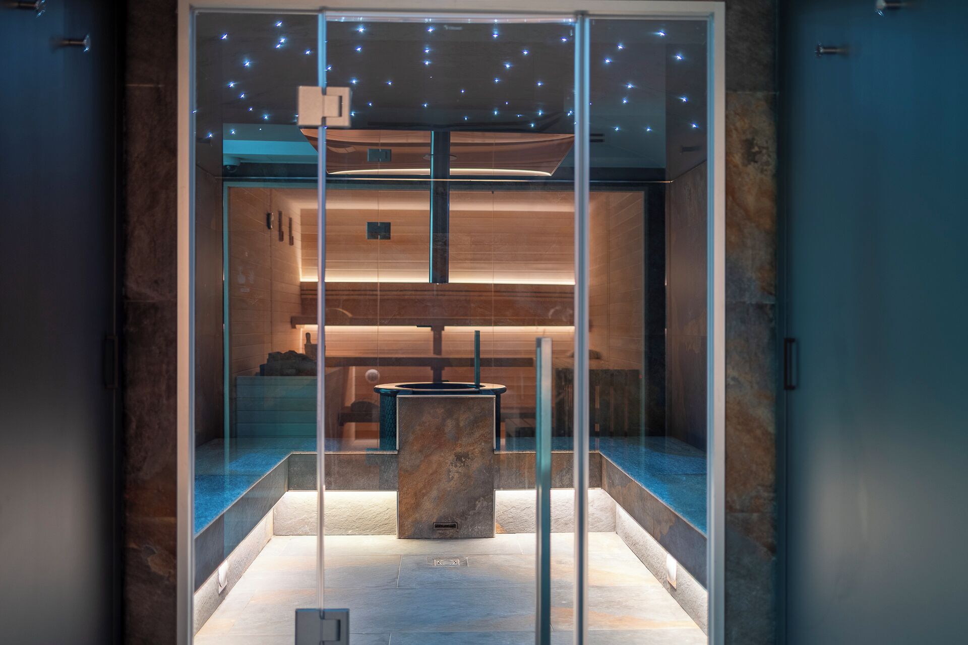 A modern bathroom with a glass enclosure, a central sink, and a ceiling with star-like lights.