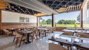 A restaurant with a modern interior, featuring marble flooring, wooden tables and chairs, and large windows offering a view of the outdoors. - Weekender Resort (Udaipur)