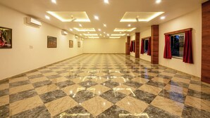 A spacious, well-lit room with a checkered floor, recessed ceiling lights, and framed artwork on the walls. - Weekender Resort (Udaipur)