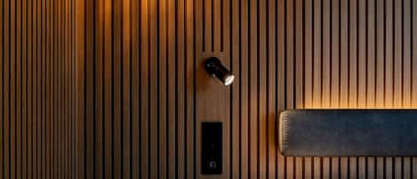 Une chambre d’hôtel avec un mur en lambris de bois, une table de chevet avec une lampe et un lit doté d’une tête de lit.