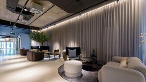 A modern lounge area with a round seating arrangement, a large potted plant, and a curtain wall.