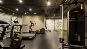 A gym with treadmills, elliptical machines, and a weightlifting station.