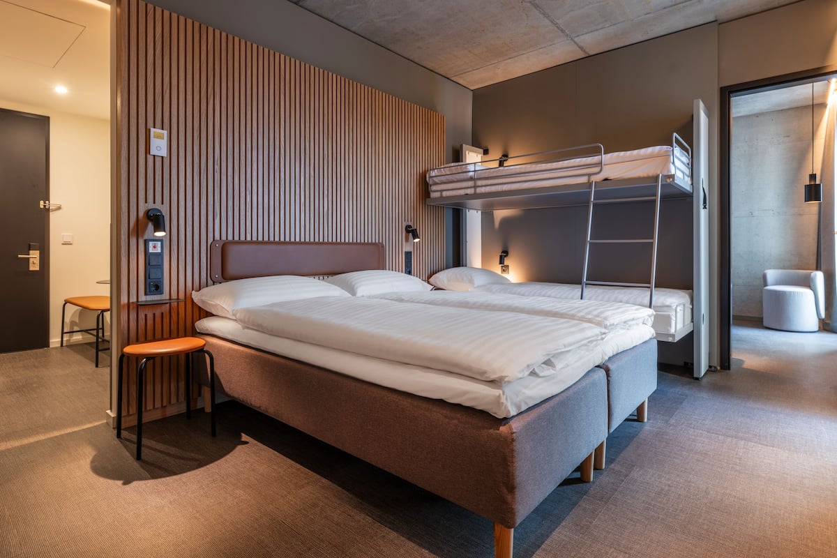 Une chambre d’hôtel moderne équipée d’un lit superposé, d’un bureau et d’une chaise.