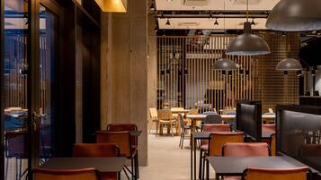 Un interior de restaurante moderno con muebles de madera, iluminación colgante y vistas a través de una puerta de cristal.