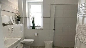 A modern bathroom with a bathtub, toilet, and shower.