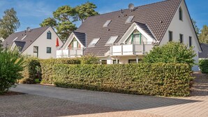 Una hilera de casas modernas con techos inclinados, paredes blancas y detalles en verde.