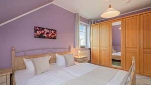 Une chambre à coucher avec un lit, une armoire en bois et une fenêtre avec des rideaux.