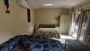 A bedroom with a bed, a nightstand, a dresser, and a window with a view.