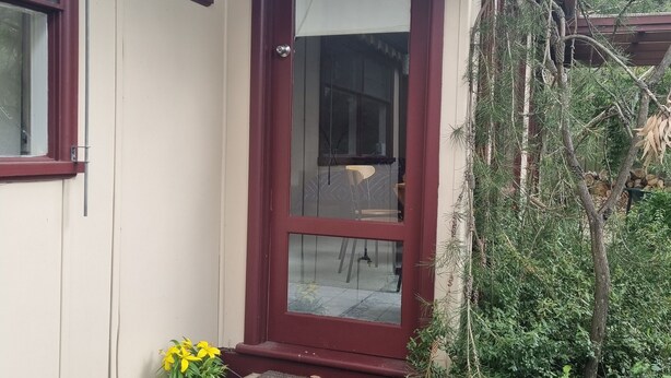 A house entrance with a red door, a small porch, and a potted plant.