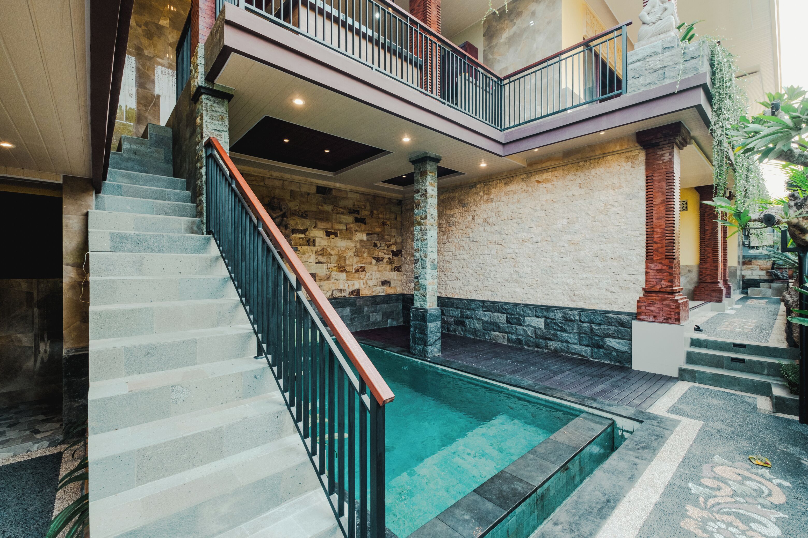 A multi-level interior with a central staircase, stone walls, and a small pool area.