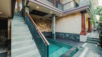 A multi-level interior with a central staircase, stone walls, and a small pool area.