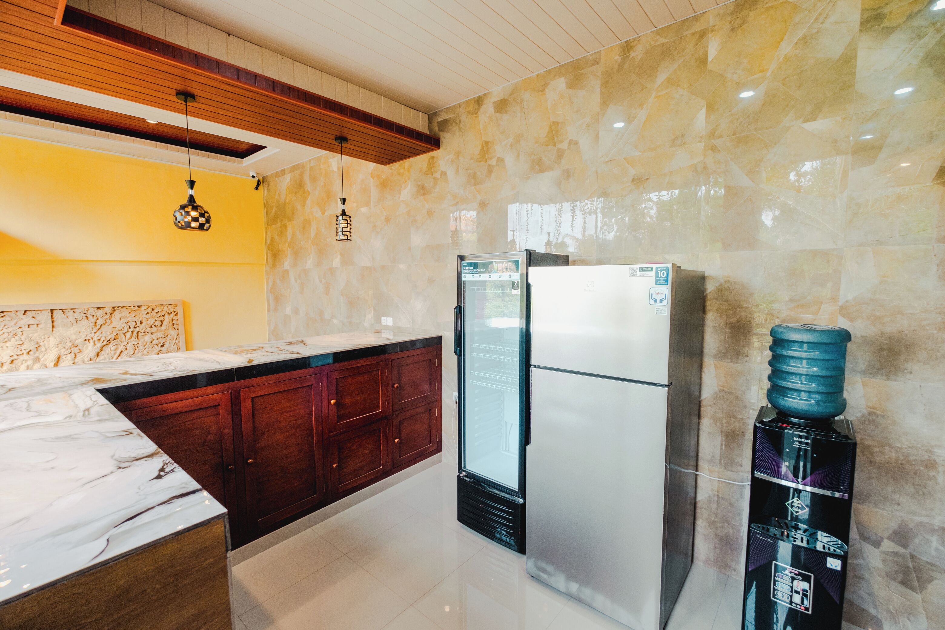 A modern kitchen with marble countertops, a built-in refrigerator, and a water dispenser.