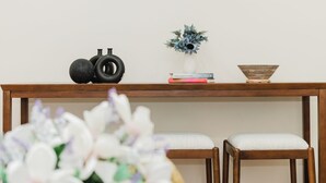 A wooden console table with a vase of flowers, a stack of books, and a bowl. Two upholstered chairs are in front. - Stylish 4 Bedroom Townhouse in Boston, Walkable to Train, Quiet & Safe Area 76 (Boston)