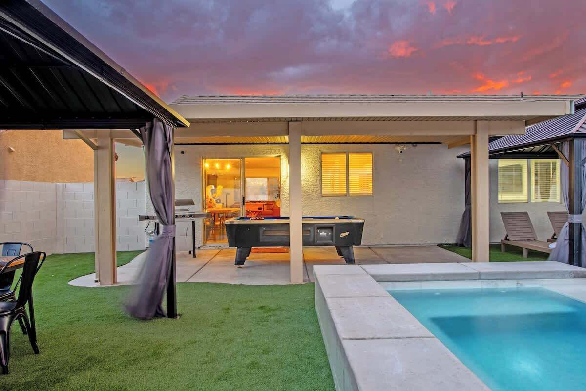 Un jardin avec une piscine, un espace barbecue et une table de billard.