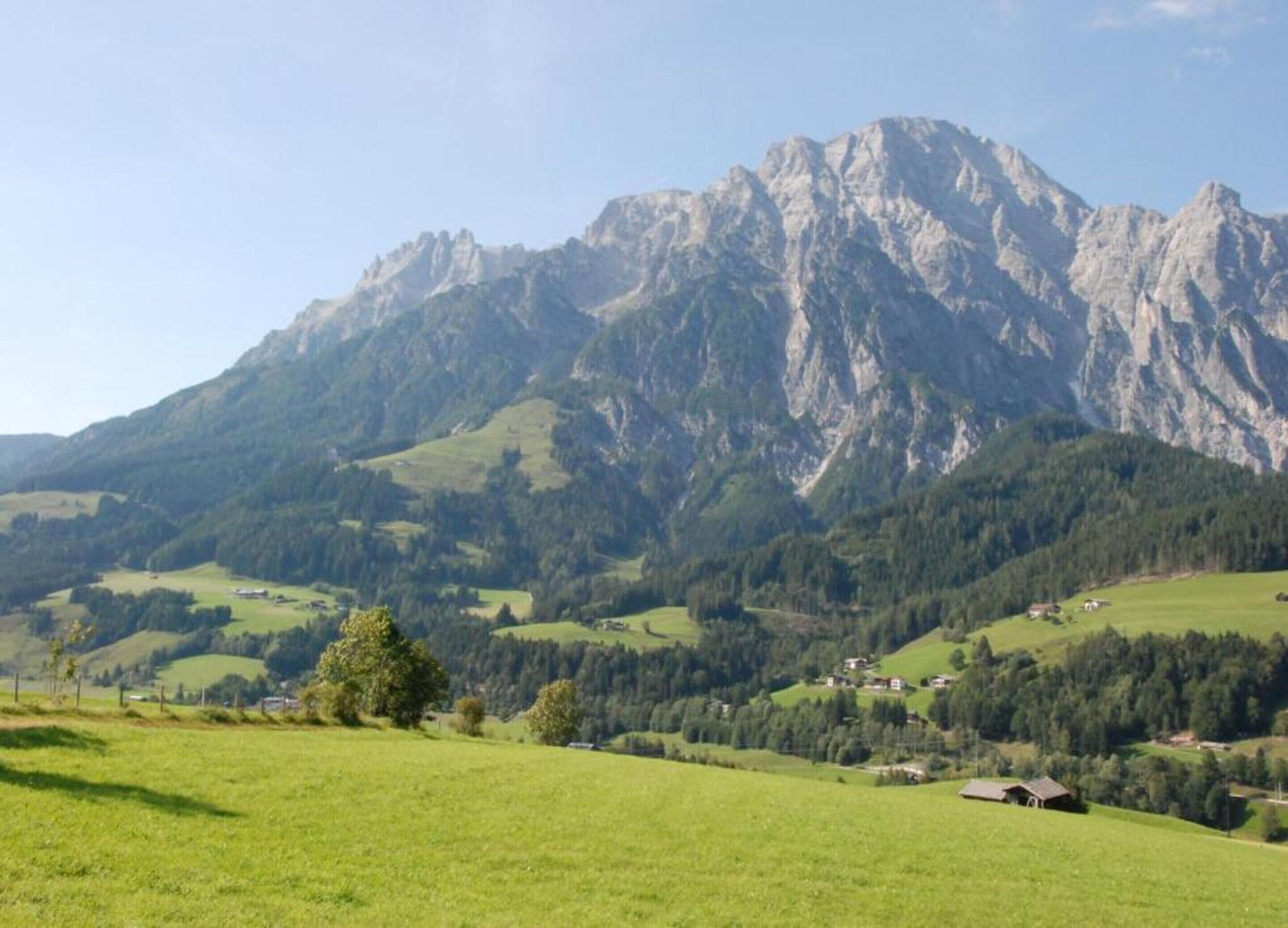 Eine Berglandschaft mit grünen Feldern und verstreuten Häusern.