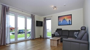 A modern living room with a grey sofa, a wooden coffee table, and a TV mounted on the wall. - Appartement Hafenflair am Plauer See (Plau am See)
