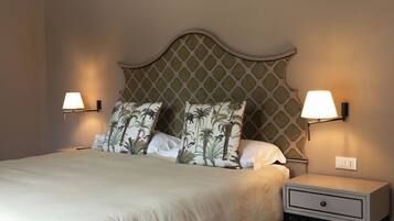 A neatly made bed with a patterned headboard, two bedside lamps, and a nightstand with a drawer.