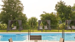Un espace aménagé au bord de la piscine, comprenant une table et des chaises, des chaises longues et un coin salon abrité.