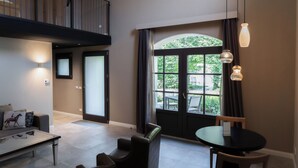 Un salon moderne comprenant une table à manger, des sièges confortables, une grande fenêtre donnant sur un espace verdoyant et un balcon avec une balustrade.