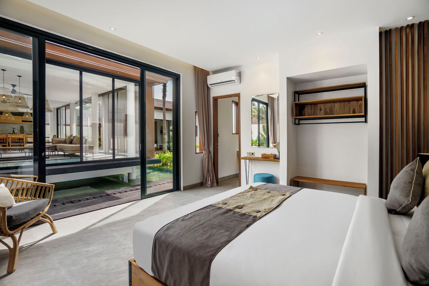 Ein modernes Hotelzimmer mit einem großen Bett, einem Schreibtisch, einem Stuhl und Blick auf einen Außenbereich.