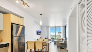 Une cuisine moderne dotée d’un réfrigérateur en acier inoxydable, de meubles de rangement en bois et d’un coin repas avec une table et des chaises.