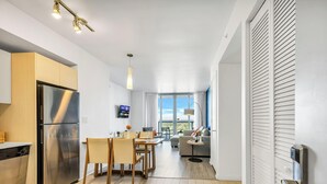 A modern kitchen with a stainless steel refrigerator, wooden cabinets, and a dining area with a table and chairs.