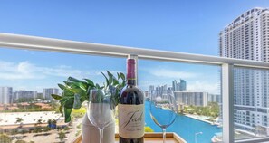 A balcony with a city view, a bottle of wine, and two glasses.