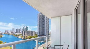 A balcony with a view of a cityscape, a river, and a tall building.