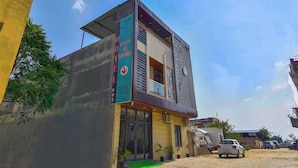 A hotel with a sign indicating full AC and rooms, a modern design, and a parking area with vehicles. - Hotel Bilaspur Pride (Gurugram)