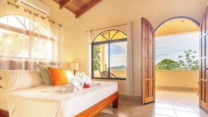 A bedroom with a large bed, a window with a view, and an open door leading to a balcony. - Gated Community-Privacy, Ocean Views-pool-Ojochal-sleep 9 (Ojochal)