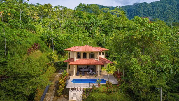 A two-story house with a red-tiled roof, a swimming pool, and lush greenery surrounding it. - Gated Community-Privacy, Ocean Views-pool-Ojochal-sleep 9 (Ojochal)