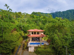 A two-story house with a red-tiled roof, a swimming pool, and lush greenery surrounding it. - Gated Community-Privacy, Ocean Views-pool-Ojochal-sleep 9 (Ojochal)