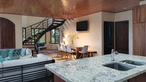 A modern kitchen with a granite countertop, a built-in sink, and a dining area with a table and chairs. - Gated Community-Privacy, Ocean Views-pool-Ojochal-sleep 9 (Ojochal)