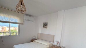 A bedroom with a bed, bedside tables, a hanging light fixture, a window with a view, and a black sofa. - Your Sanctuary with a View of History: Live Córdoba from the Heart of the City (Córdoba)