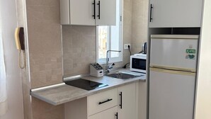 A compact kitchen with white cabinets, a built-in microwave, and a refrigerator. - Your Sanctuary with a View of History: Live Córdoba from the Heart of the City (Córdoba)