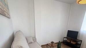 A modern living room with a sofa, a coffee table, a TV stand, and a hanging light fixture. - Your Sanctuary with a View of History: Live Córdoba from the Heart of the City (Córdoba)