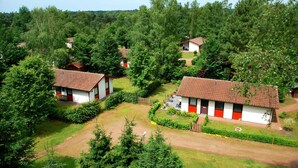 Un gruppo di edifici bianchi con dettagli rossi, immersi in un lussureggiante verde e alberi.